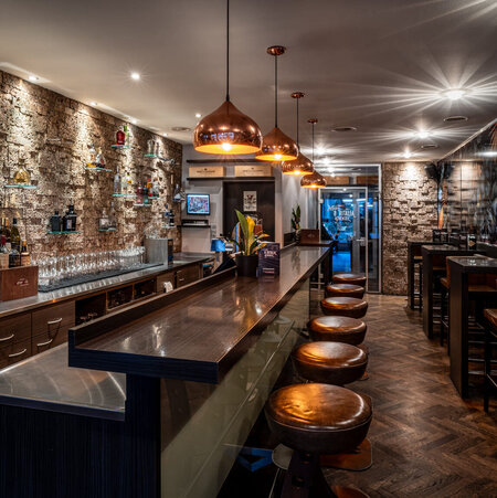 Full view of the bar with illuminated shelves and high bar stools